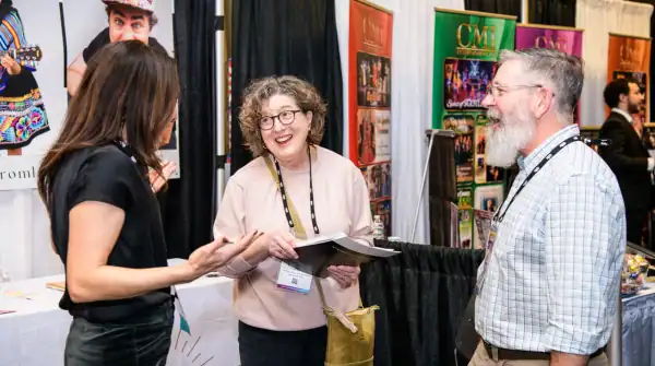 A man and woman talking to another woman in the APAP|NYC Expo Hall (Photo by Adam Kissick/APAP)