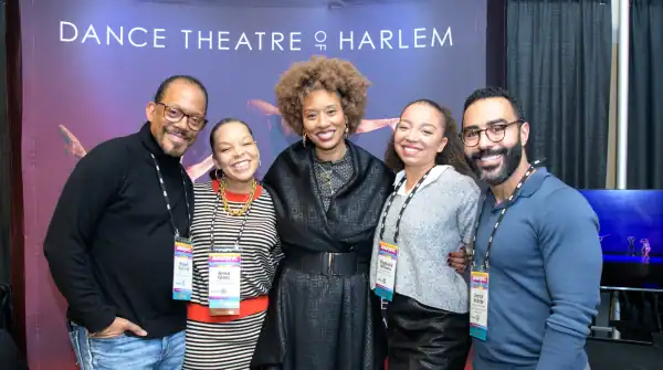 Two APAP members shaking hands and talking in the EXPO hall. The background includes other APAP members in conversation with one another.